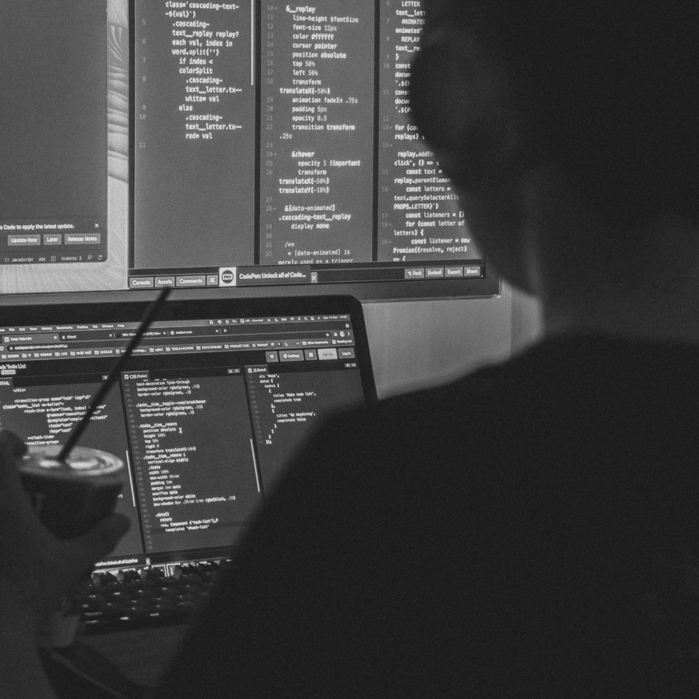 A developer working across laptop and desktop screens